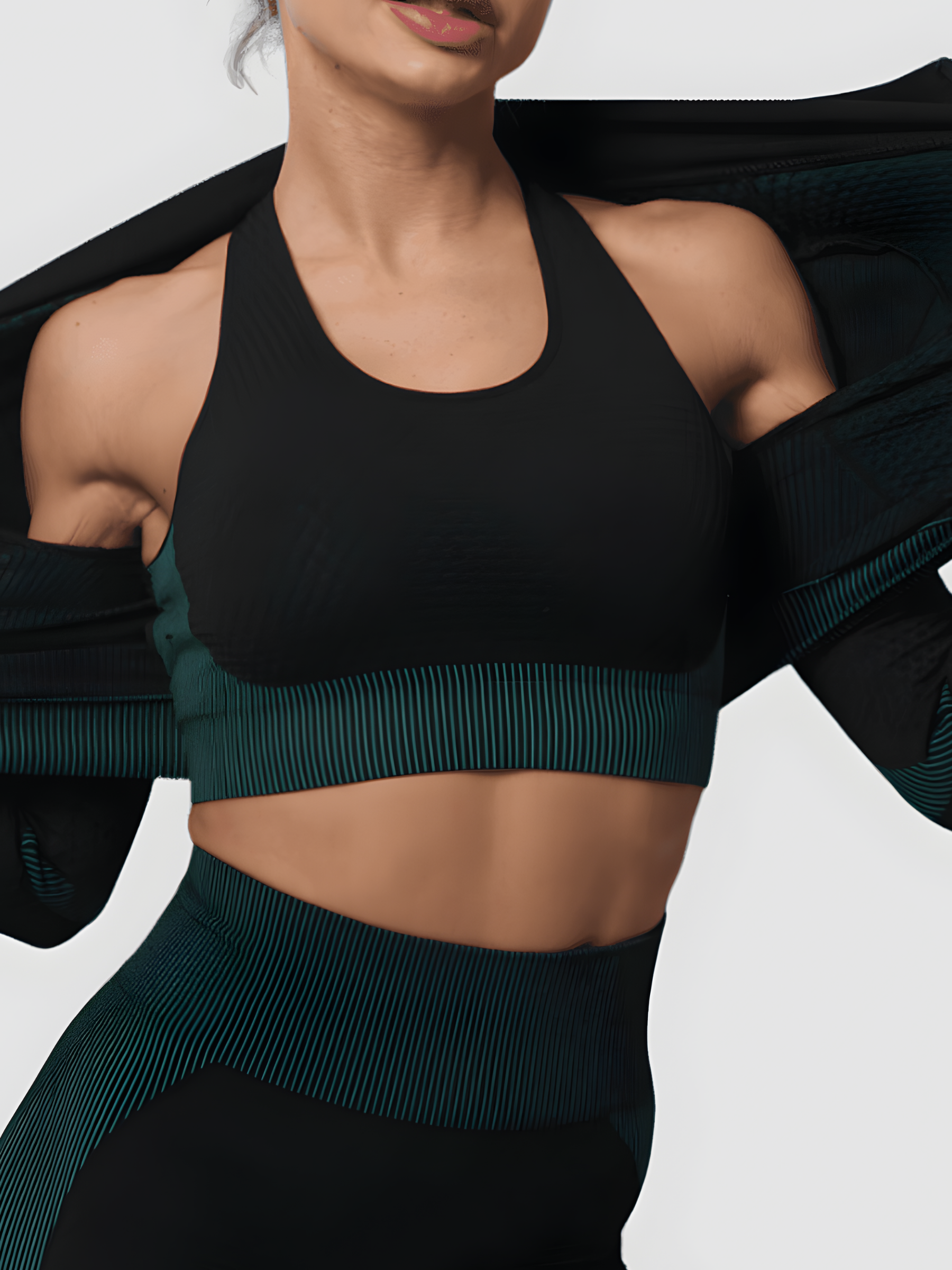 Woman wearing a padded black and teal textured sports bra with matching leggings and activewear jacket by BodyFlexx.