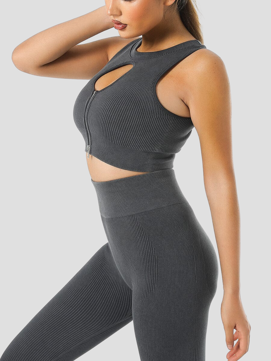 Woman wearing a ribbed black halter sports bra with a peekaboo hole in the front and matching leggings.
