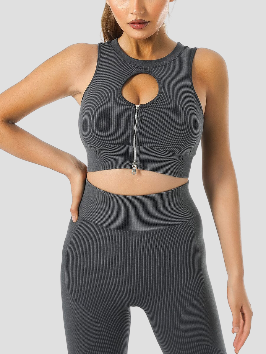 Woman wearing a ribbed black halter sports bra with a peekaboo hole in the front and matching leggings.