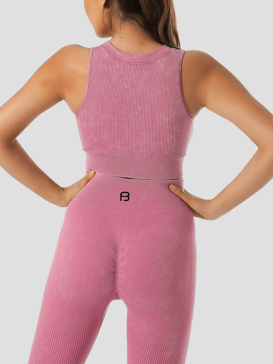 Woman showing the back of a ribbed pink halter sports bra and matching leggings.