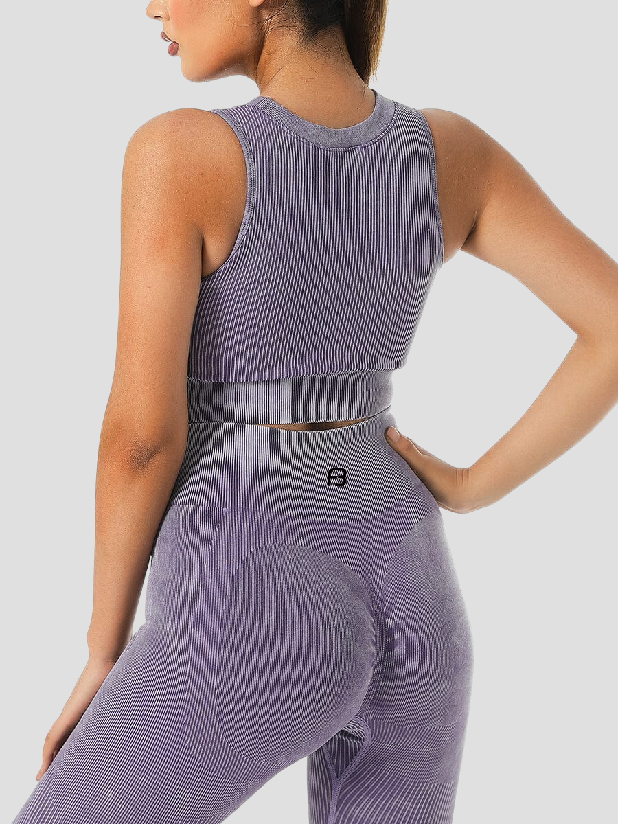 Woman showing the back of a ribbed pink halter sports bra and matching leggings with the BodyFlexx logo visible.