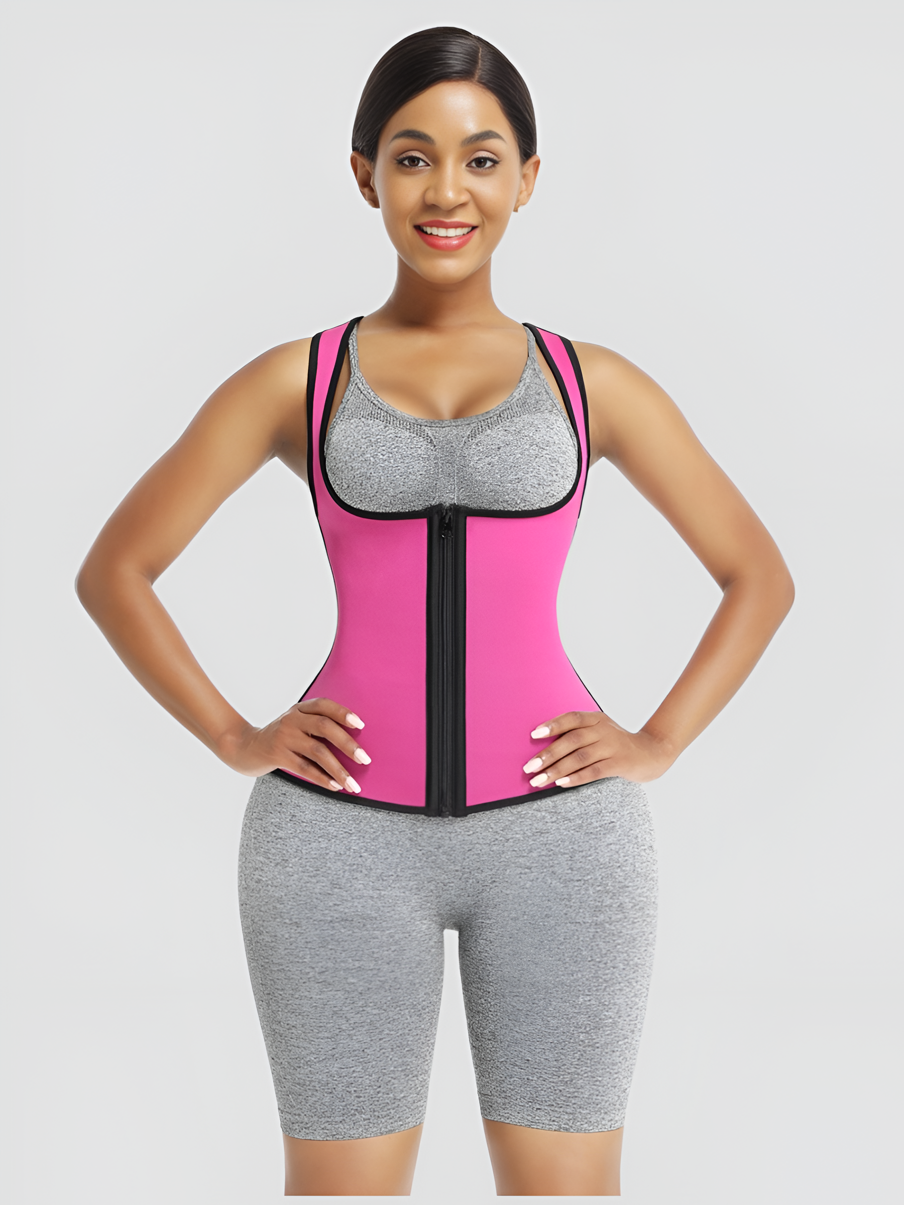 Woman wearing a pink and black waist trainer sauna top against a gray background.
