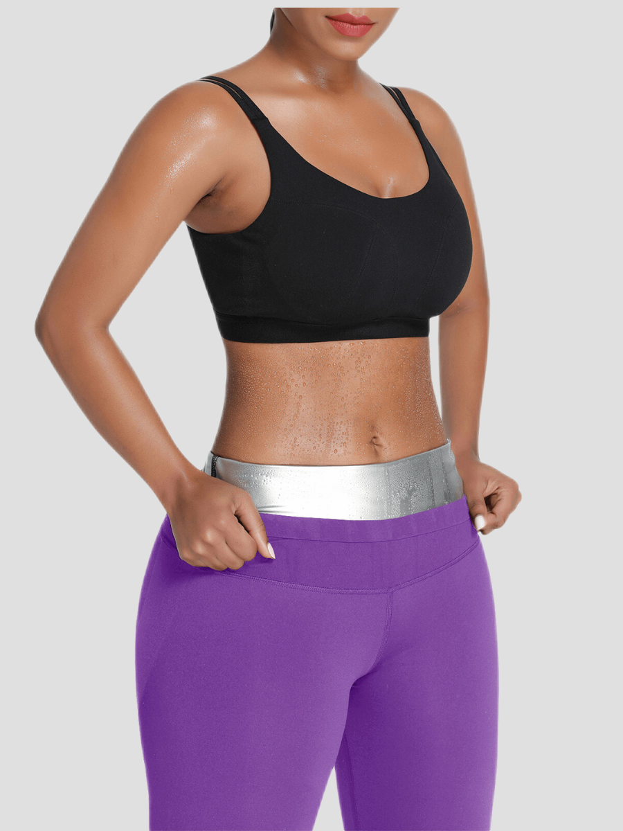 Woman wearing purple sauna activewear shorts and a black sports top showing the neoprene lining and how much her stomach sweated during her workout.