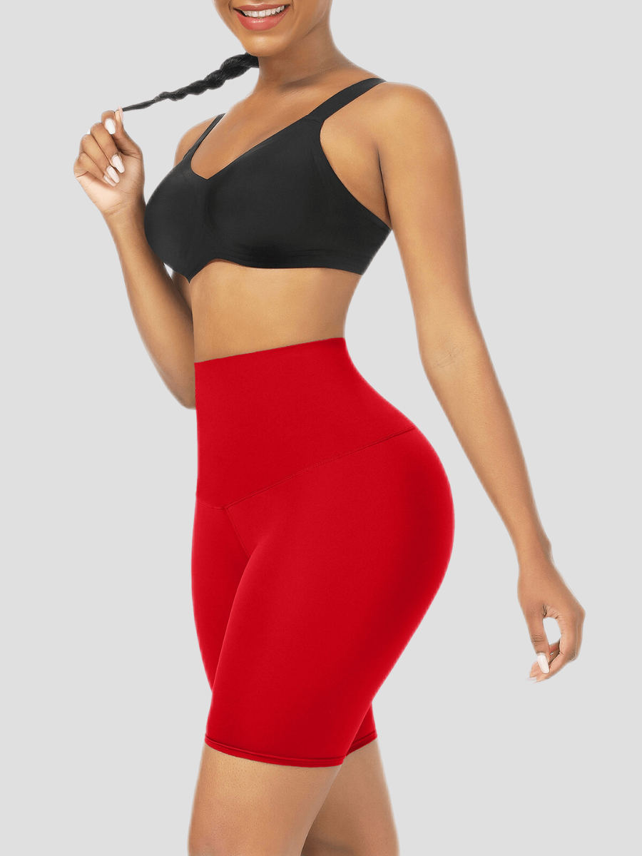 Woman wearing red sauna activewear shorts and a black sports bra smiling after a workout.