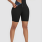 Woman wearing black mid-thigh BodyFlexx Waist-Training Sauna Shorts with a corset closure showing a sweaty stomach after a good workout.