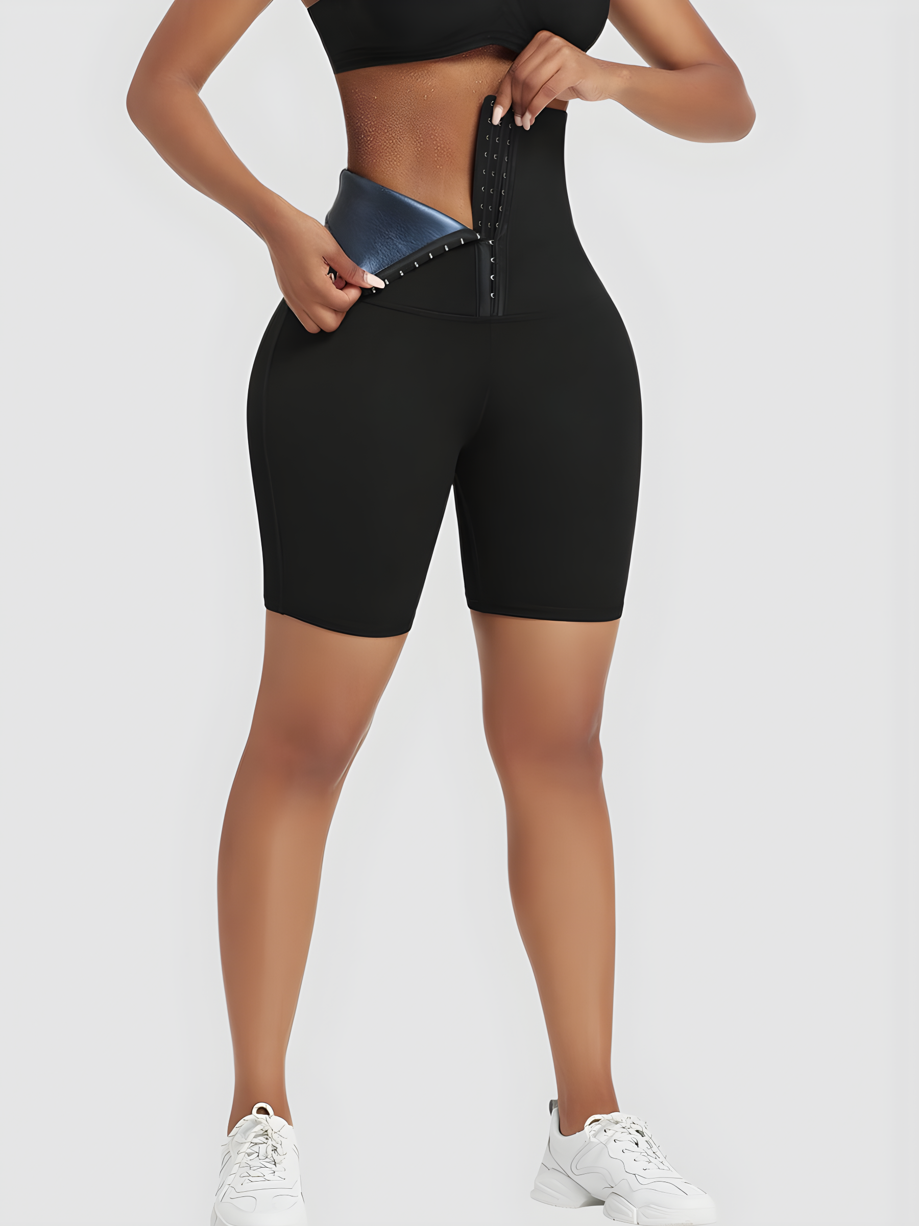 Woman wearing black mid-thigh BodyFlexx Waist-Training Sauna Shorts with a corset closure showing a sweaty stomach after a good workout.