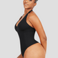 Woman posing wearing a black halter-style shapewear bodysuit with built-in removable bra padding and seamless thong design. She is posing to show off her curves.