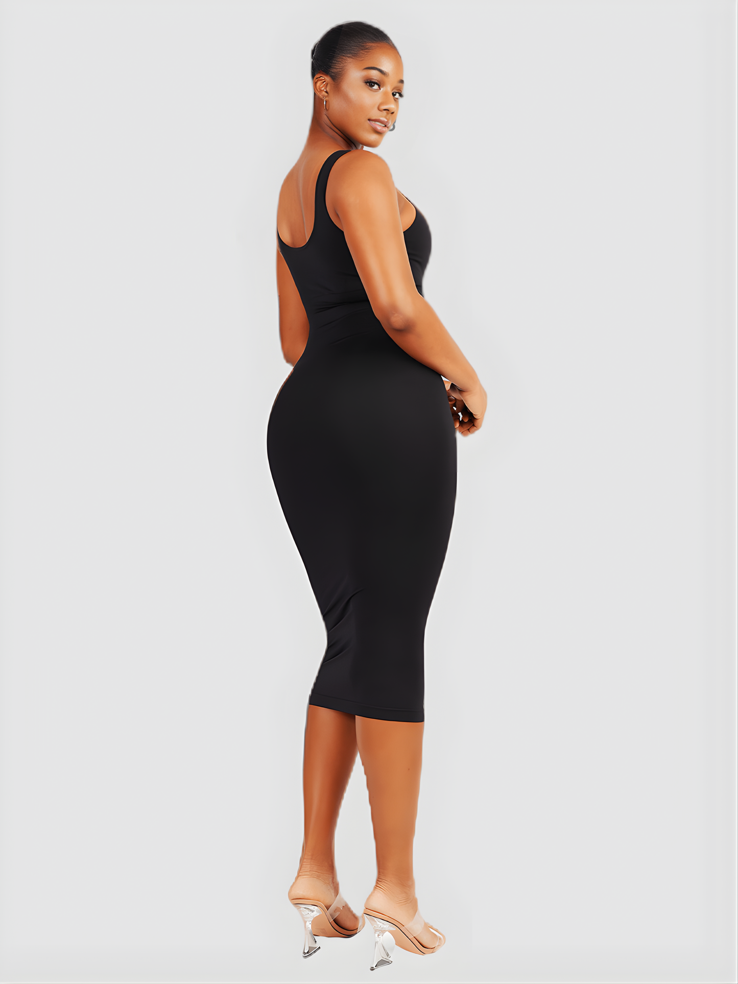 Woman wearing a black sleeveless sculpting dress with built-in shapewear by BodyFlexx.