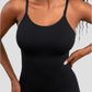 Model wearing a black shapewear camisole with tummy control and adjustable straps.