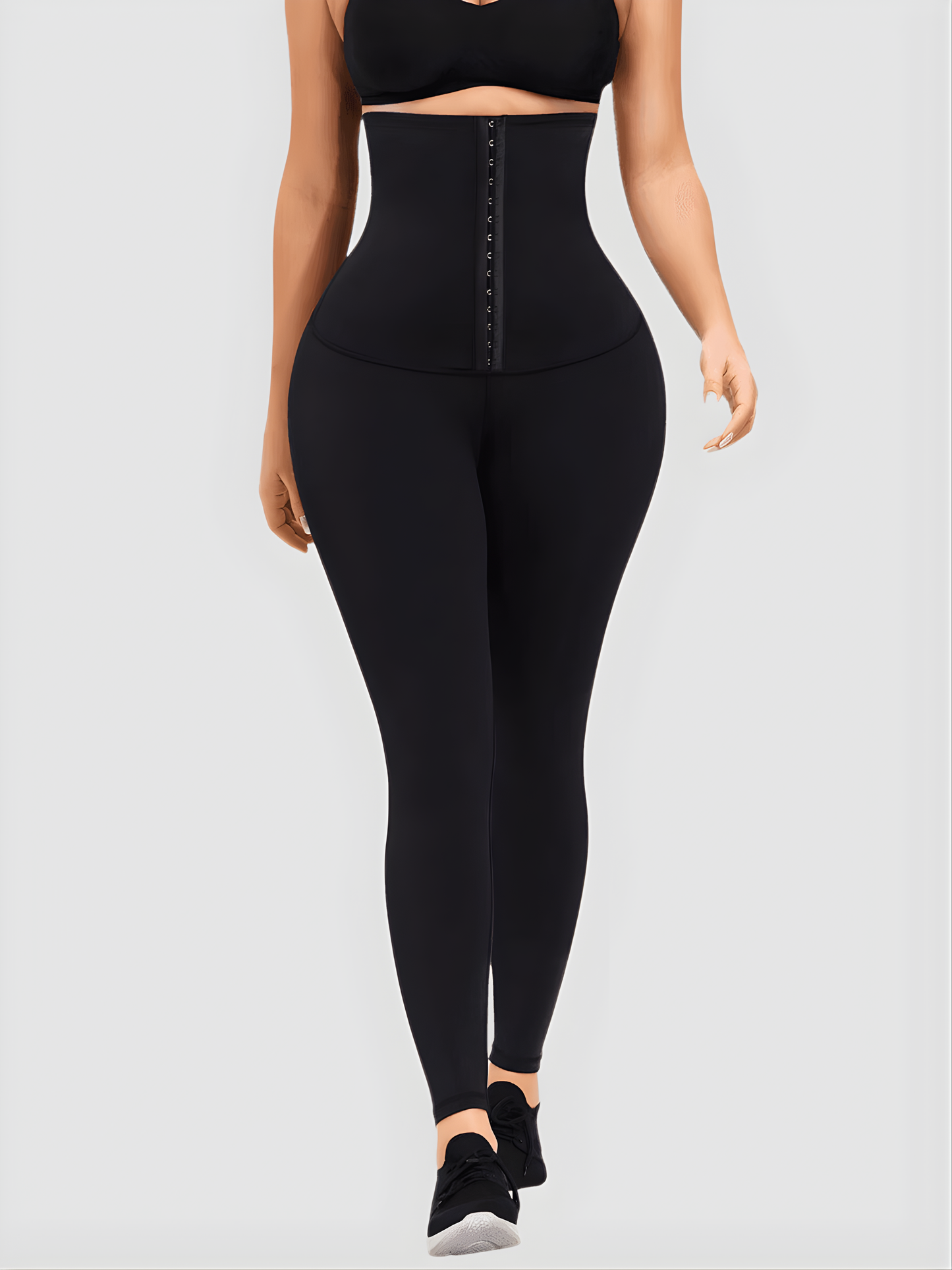 Woman wearing black waist training leggings with an extra high corset-style closure to flatten her tummy and sculpt her curves.