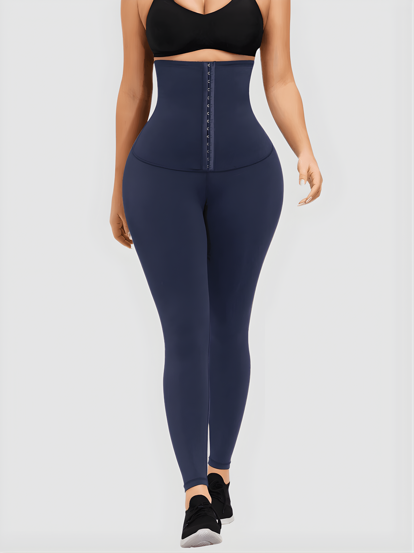 Woman wearing blue waist training leggings with an extra high corset-style closure to flatten her tummy and sculpt her curves.