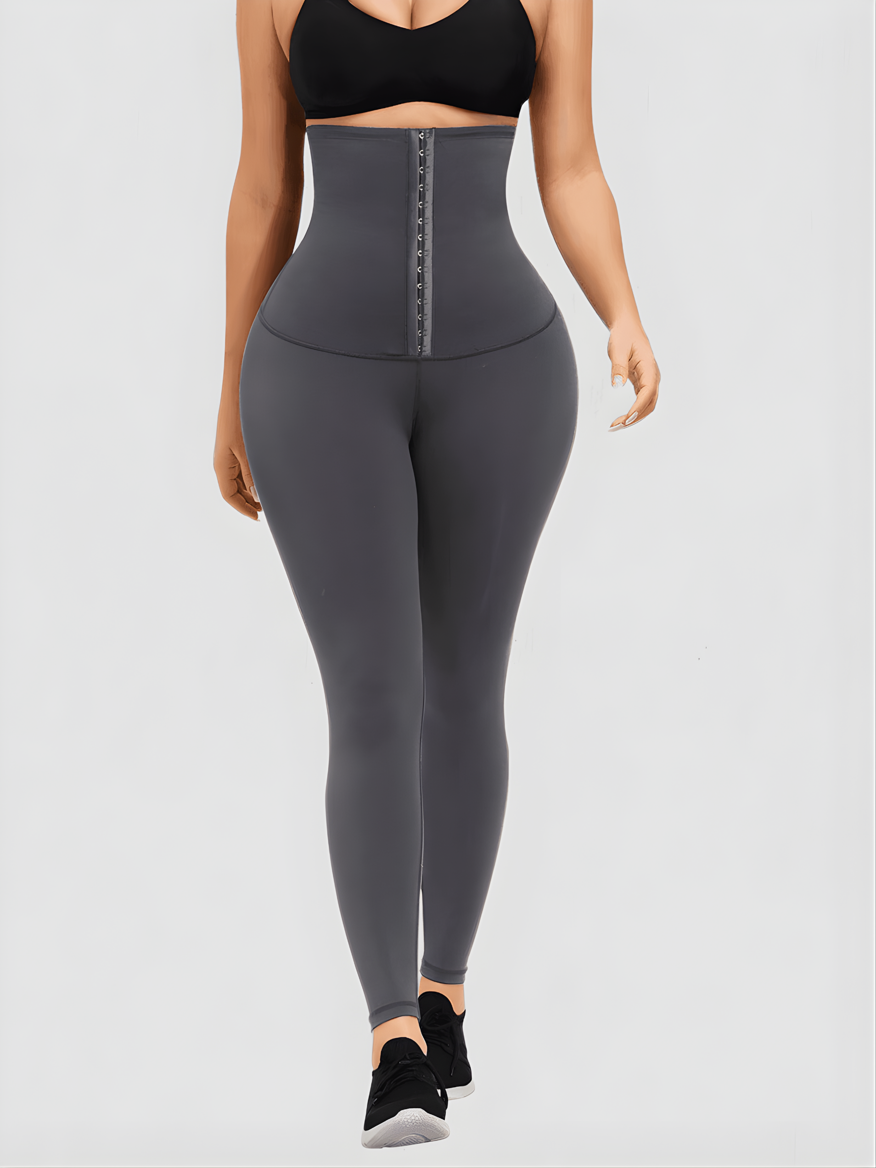 Woman wearing gray waist training leggings with an extra high corset-style closure to flatten her tummy and sculpt her curves.