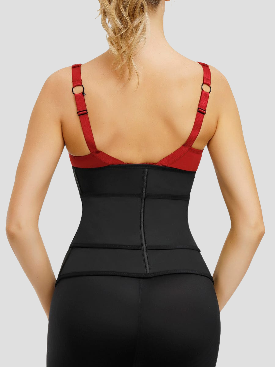 A  woman standing backwards wearing a black waist trainer and a red top showing how it is supporting her back.