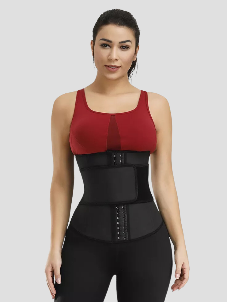 A young woman wearing a black waist trainer with a corset-style hook-and-eye closure and a high compression Velcro belt ready to workout.