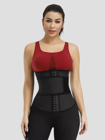 A young woman wearing a black waist trainer with a corset-style hook-and-eye closure and a high compression Velcro belt ready to workout.