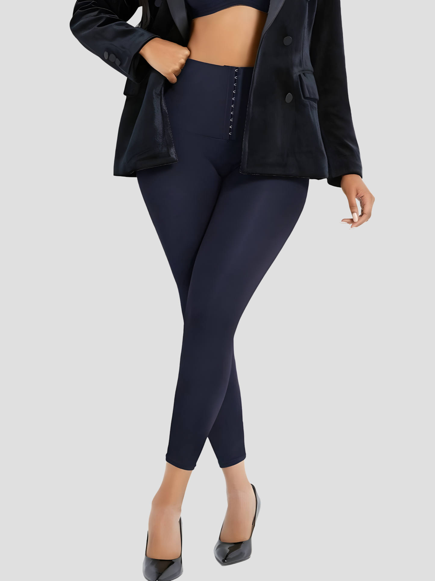 Woman wearing blue high waisted corset leggings for tummy-control paired with a black jacket.