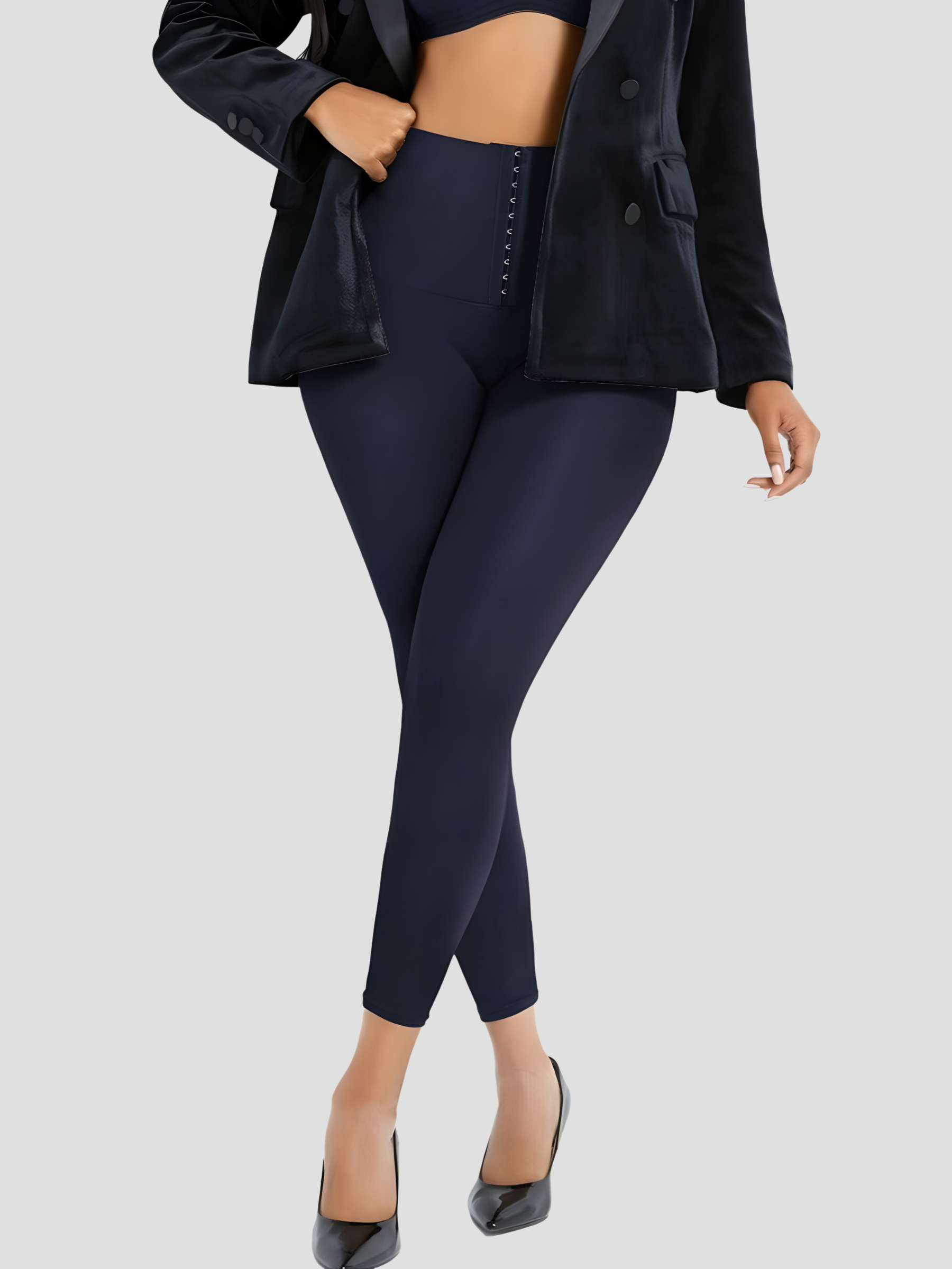 Woman wearing blue high waisted corset leggings for tummy-control paired with a black jacket.