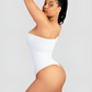 Woman posing wearing a white off-the-shoulder sleeveless shaping bodysuit with built-in shapewear for tummy-control and hourglass curves. She is showcasing the thong design.
