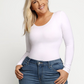Woman wearing a white long-sleeve shaping bodysuit by BodyFlexx Shapewear with blue jeans.