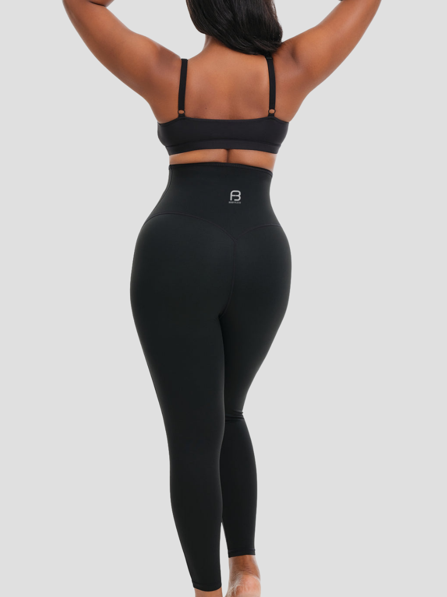 Woman wearing waist trainer leggings with a high corset-style closure in black.