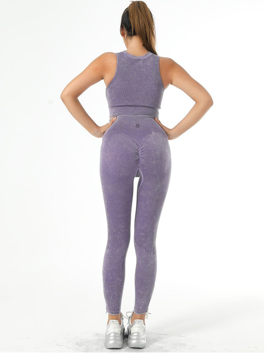 Woman wearing high-waisted ribbed purple leggings with a matching sports bra designed by BodyFlexx.
